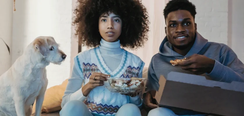 A young Black couple engrossed in a movie while streaming their favorite shows at home on the couch.